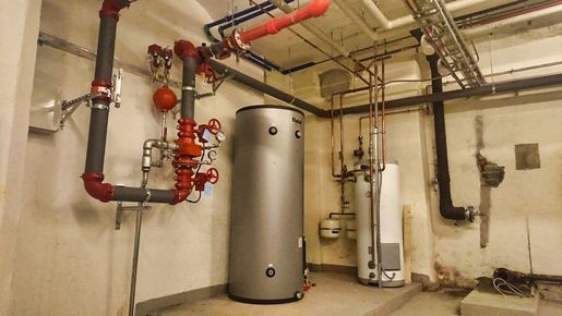 Kjeller med rørsystem i taket og en stor varmtvannsbereder
